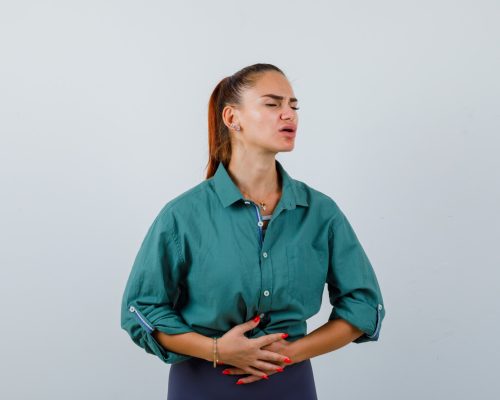 senorita-que-sufre-dolor-estomago-camisa-verde-luce-dolorosa-vista-frontal_176474-104757